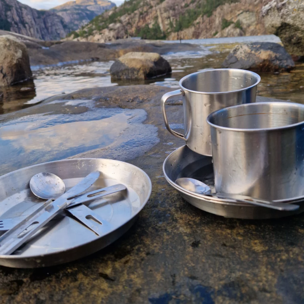 Dishes, cups, and saucers drying on a rack after being washed in the calm waters of a fjord.