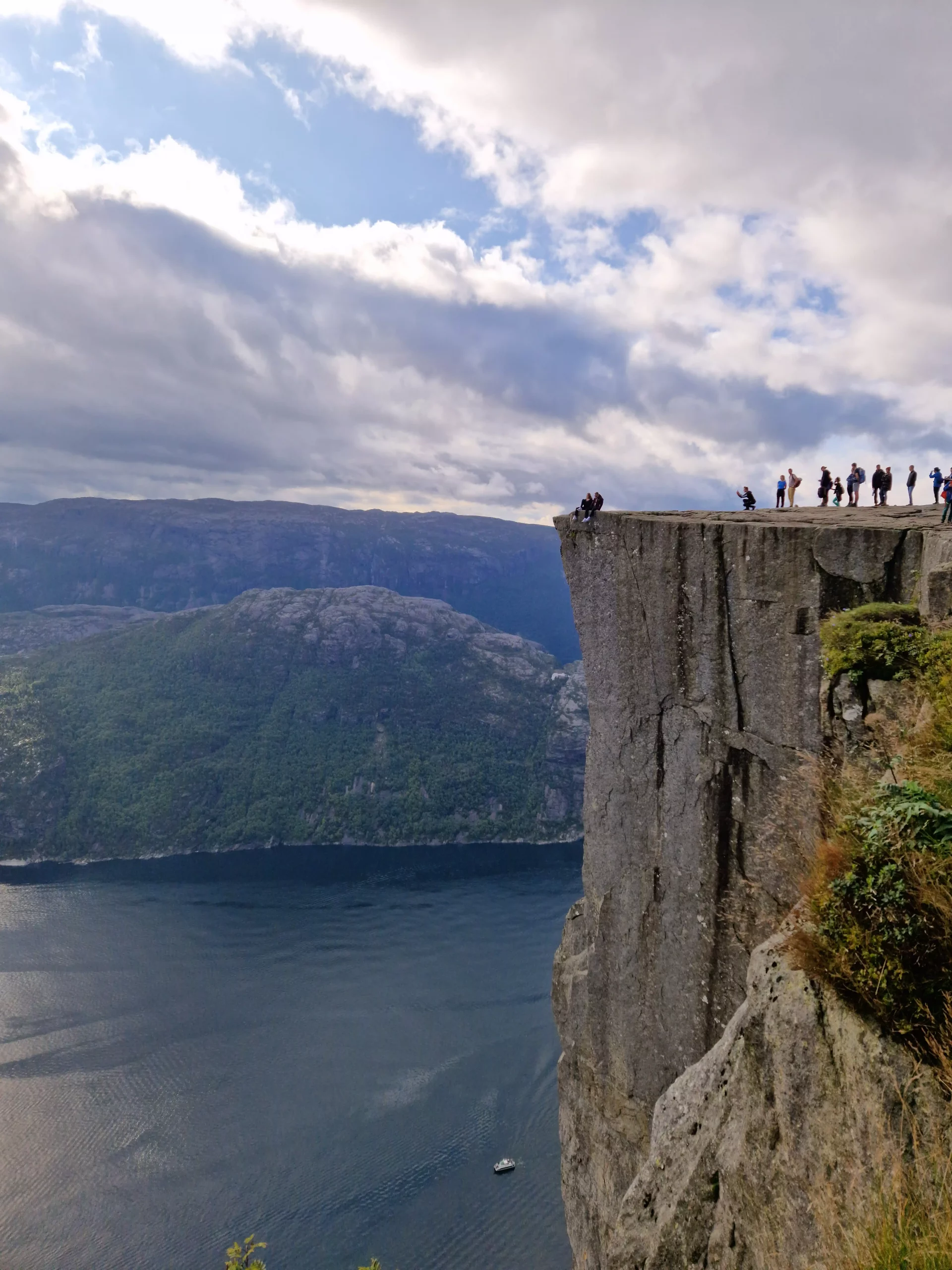 Hiker standing at the edge of Pulpit Rock (Preikestolen) overlooking the Lysefjord in Norway